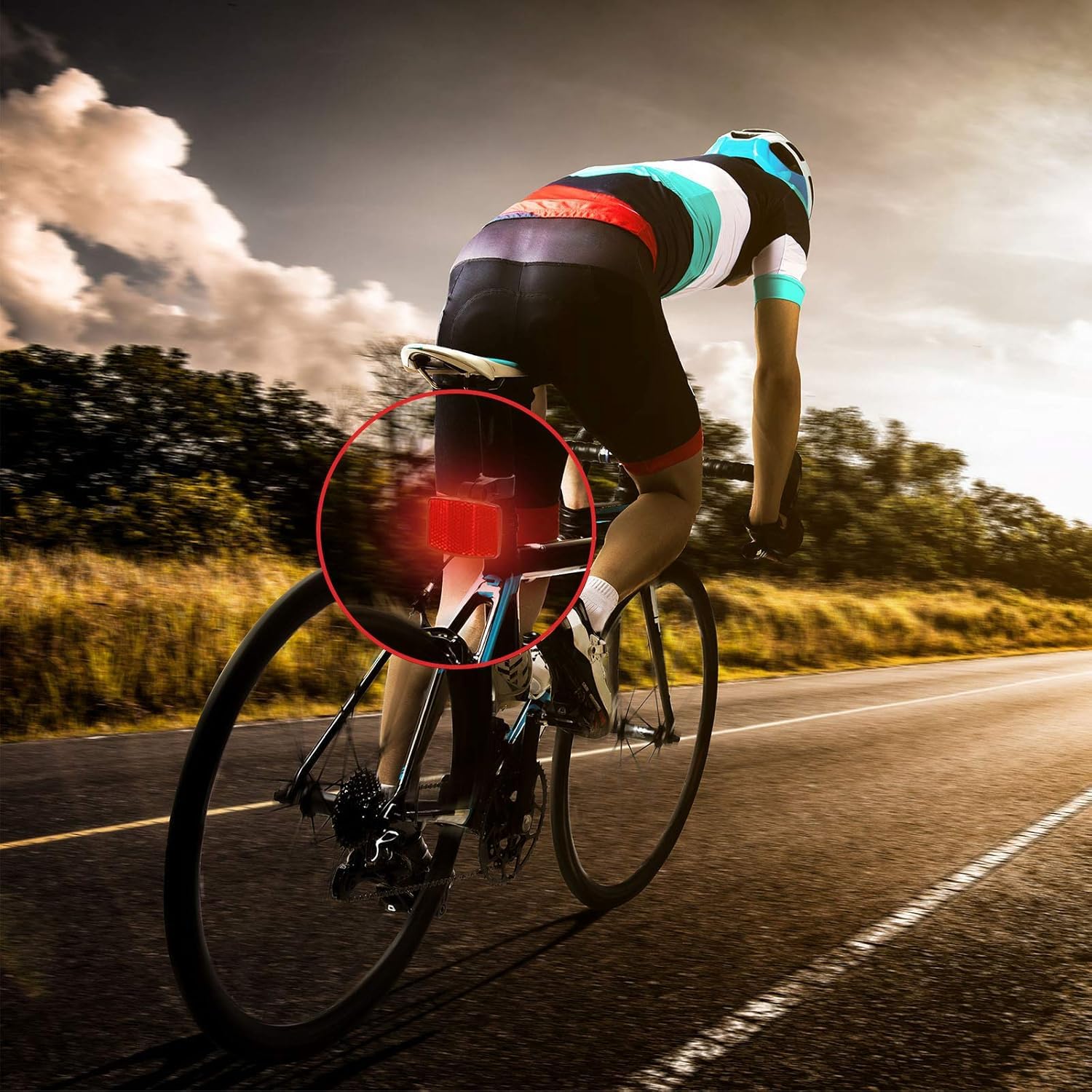 Cyclist on a road bike with a red light on the back, riding on a road with trees in the background.