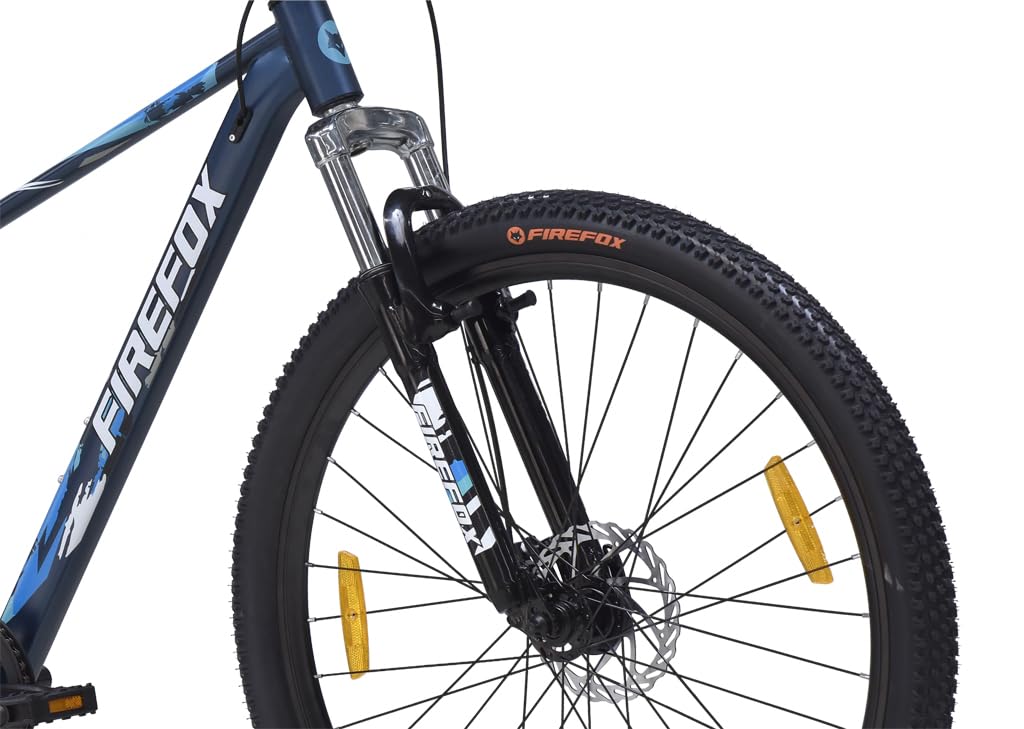 Close-up front view of the FIREFOX Tremor X 29 D mountain bike highlighting the front suspension fork, disc brake, and black tire with orange reflectors against a white background.

