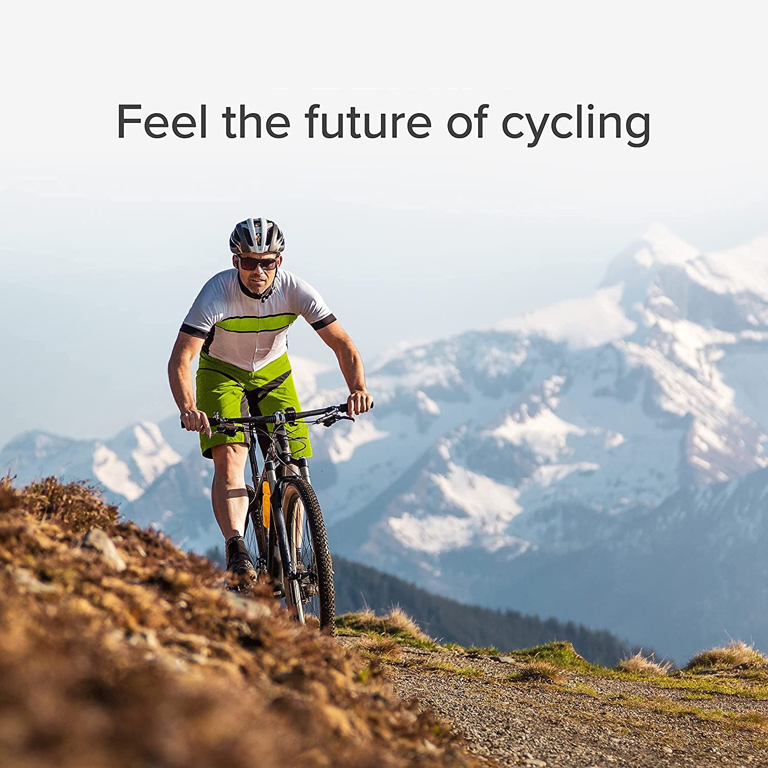 Man riding a mountain bike on a rugged trail with snow-covered peaks in the background and the text 'Feel the future of cycling' displayed above.
